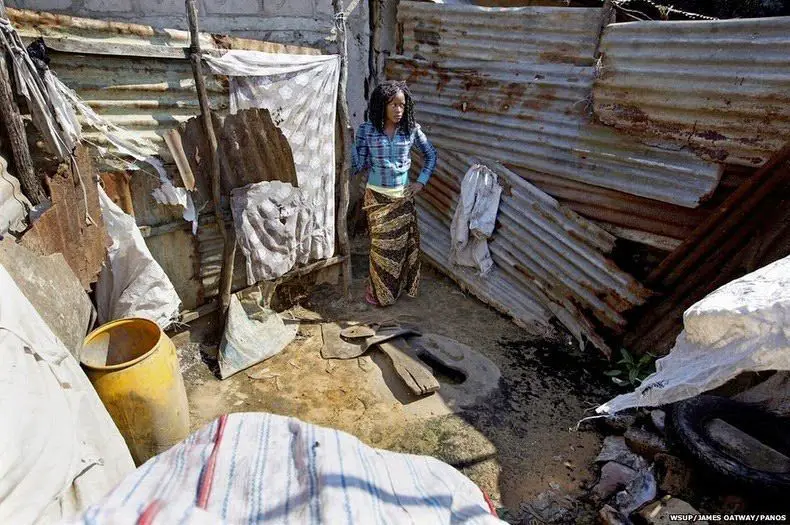 امرأة موزمبيقية أمام مرحاض متدهور خارج منزلها